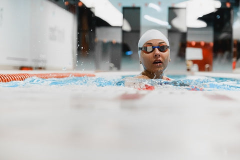 Woman swimming with swim cap on in an indoor swimming pool lane