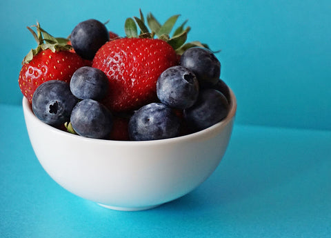 a white bowl with blueberries and strawberries