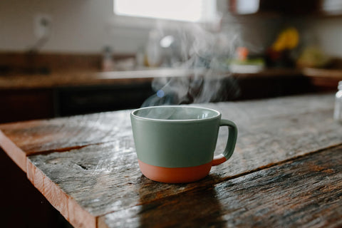 a mug with hot liquid on top of a wood table