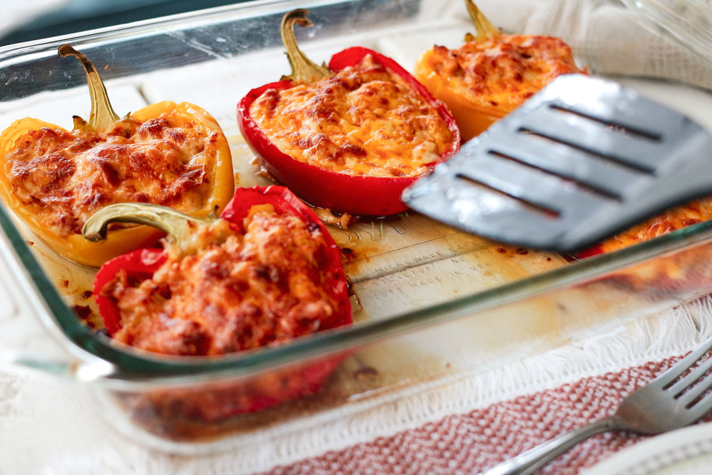 Glass casserole dish with red and yellow bell peppers cut in half and stuffed