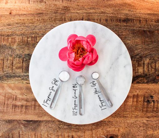 Pink Flower and Spoons Filled with Ingredients for a Sea Salt Spray on Top of a Wooden Table 
