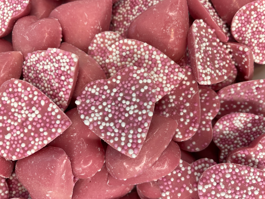 Scattered Valentine's Day cinnamon heart candies with red and pink jelly  beans on white background Stock Photo - Alamy