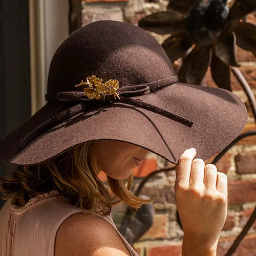 Broach pinned on brown floppy hat