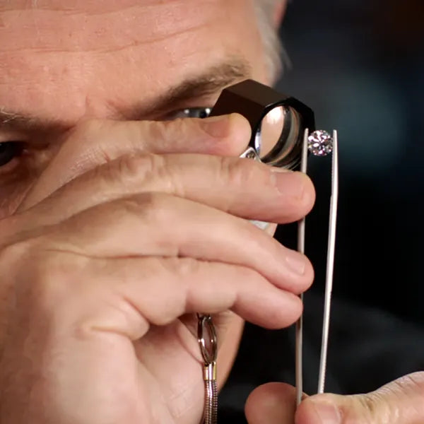 Jeweler looking at loose diamond with loop