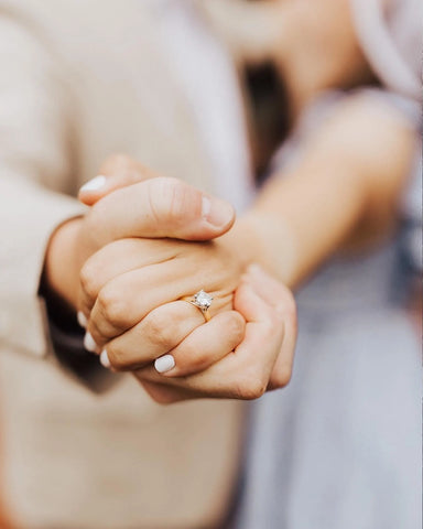 Man and Woman Holding Hands with Engagement Ring