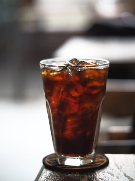 A glass of coke with ice on a wooden table