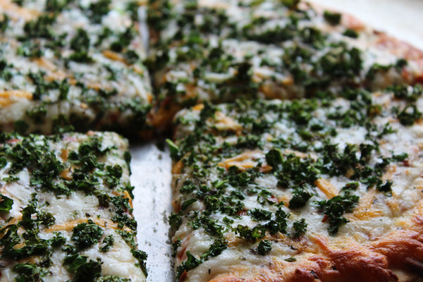 Kale & Pesto and artichoke pizza divided into slices