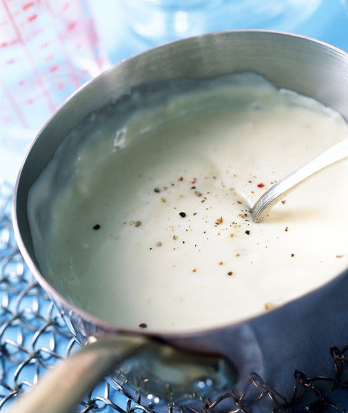 Bechamel sauce in the saucepan spiced with fresh grounded pepper