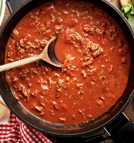 Sauce Bolognese with a wooden tablespoon in a pan
