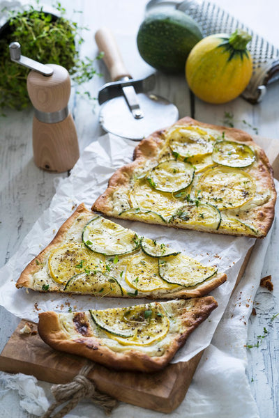 Flatbread pizza topped with zucchini slices on a wooden tray