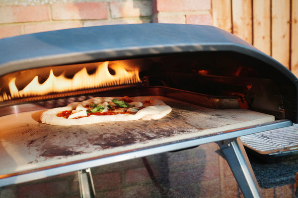 Homemade pepperoni pizza is baked in a gas pizza oven.