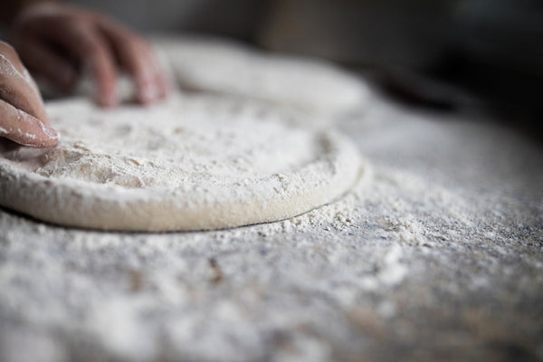 Handmade pizza dough being shaped on a table