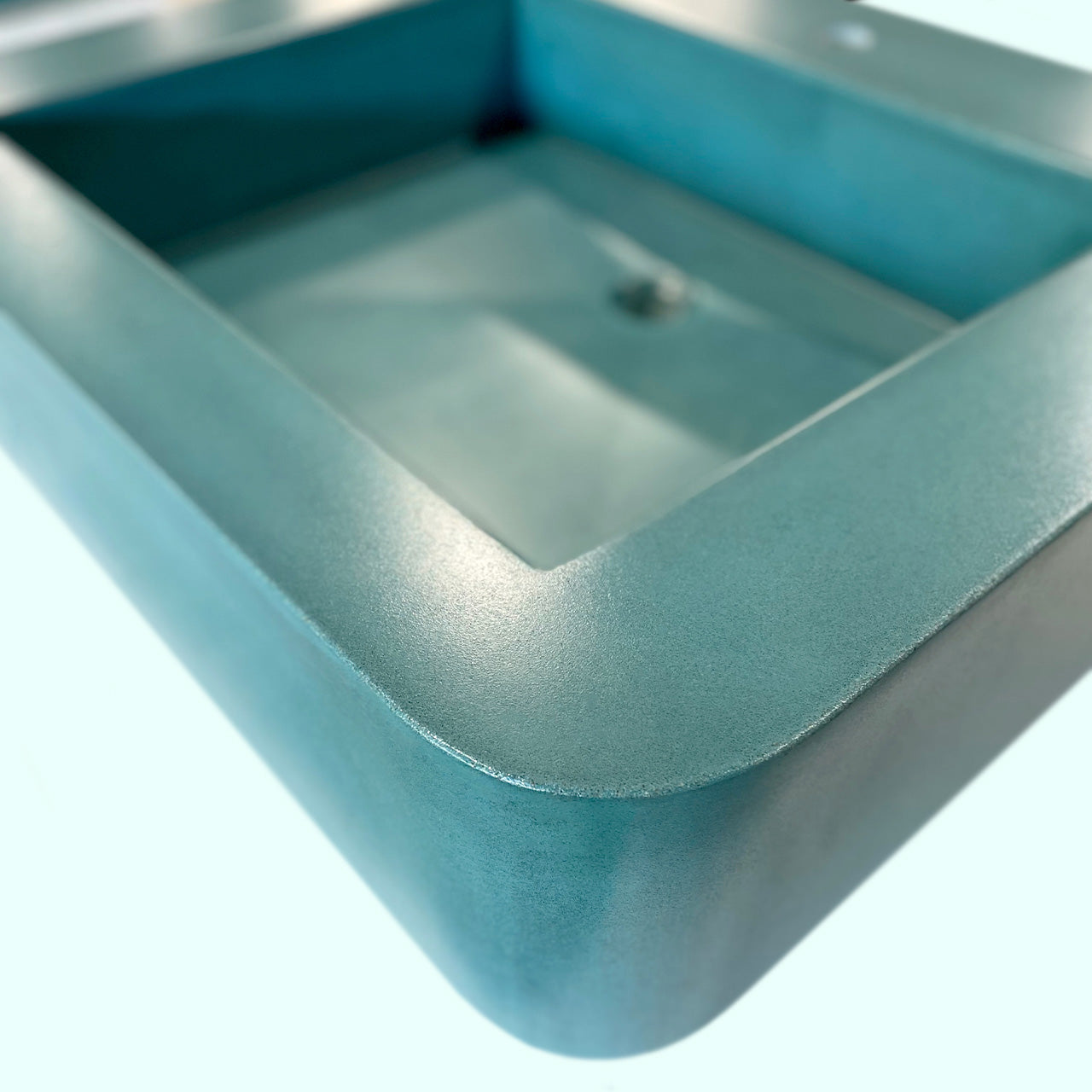 Teal concrete sink ready to be hung on the wall.