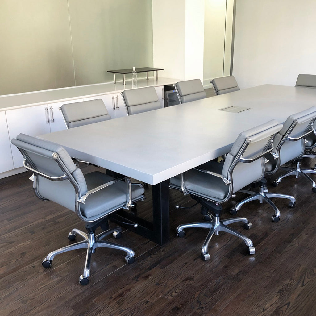 Concrete conference table surrounded by office chairs.
