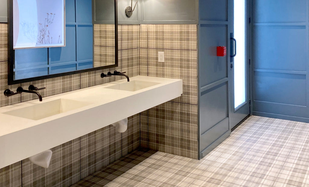 Spacious commercial bathroom with concrete sink bank on the wall.