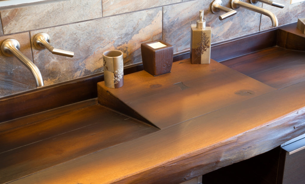 Wood look concrete commercial sink with three stations and brushed metal faucets.