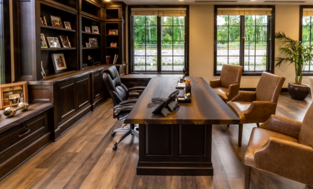 Large office space with concrete wood look desk and wood floors with leather seating.