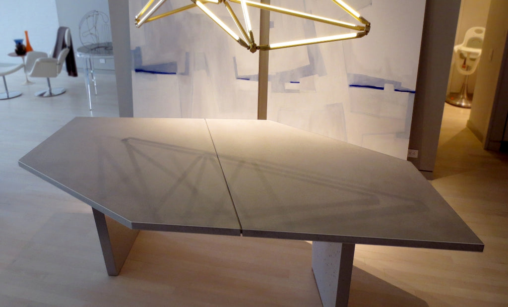 Asymmetrical concrete desk or conference table with geometric shaped lighting overhead.