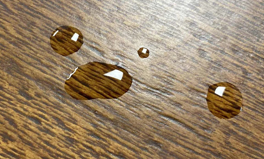 Woodform surface with water droplets beaded up on the sealed surface.