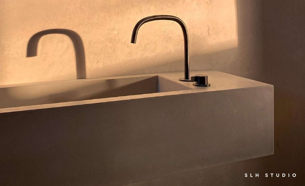 Long concrete sink with gooseneck faucet with afternoon lighting.