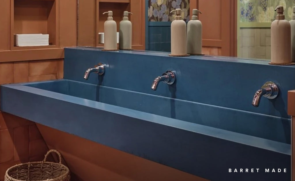 Deep blue concrete custom sink with triple stations in a wood bathroom.