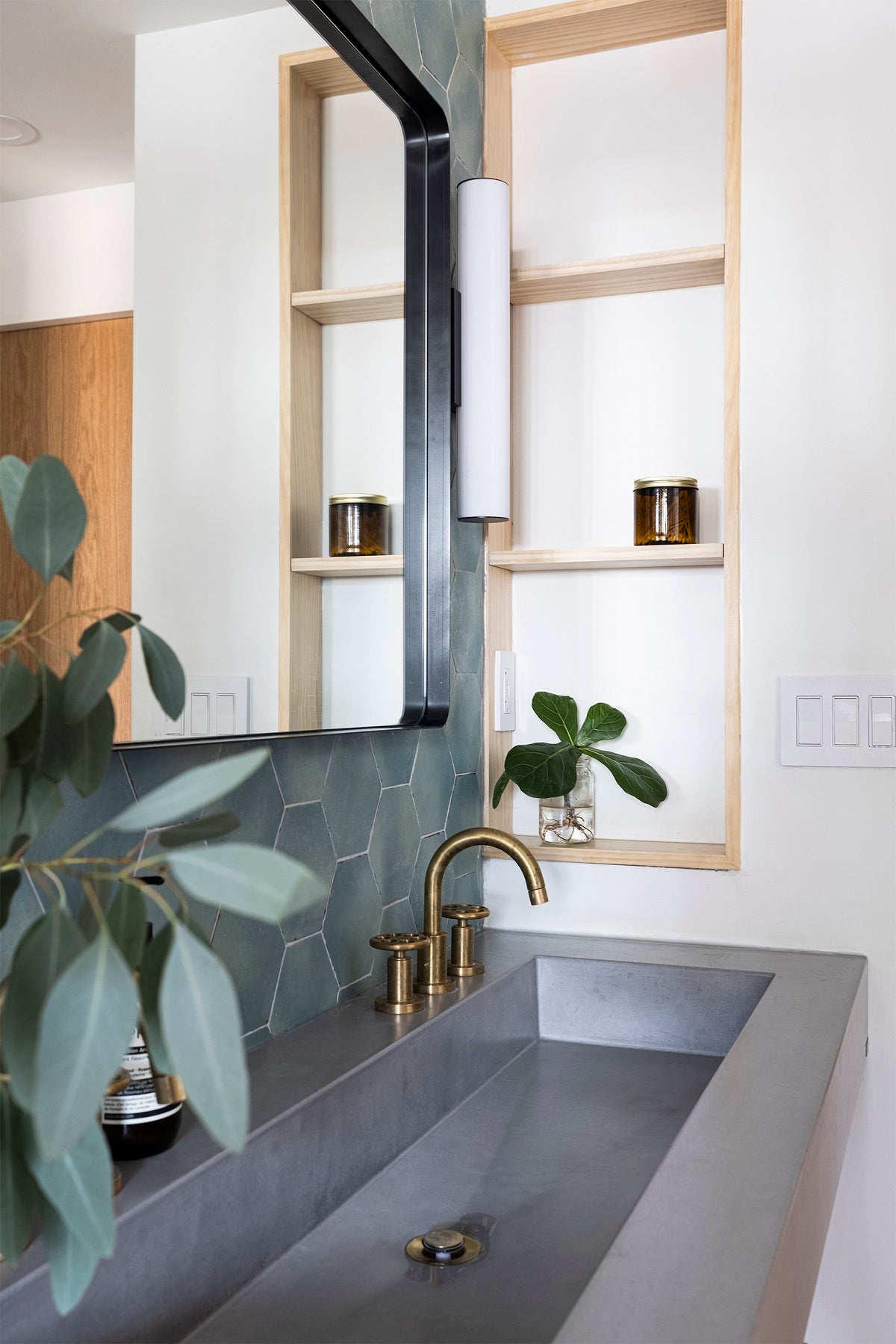 Modern bathroom with deep green tile backsplash and gray concrete double vanity.