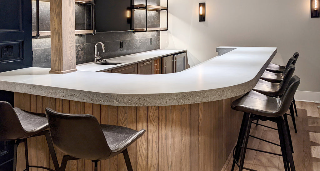 Single piece curved concrete bar top in a home bar.