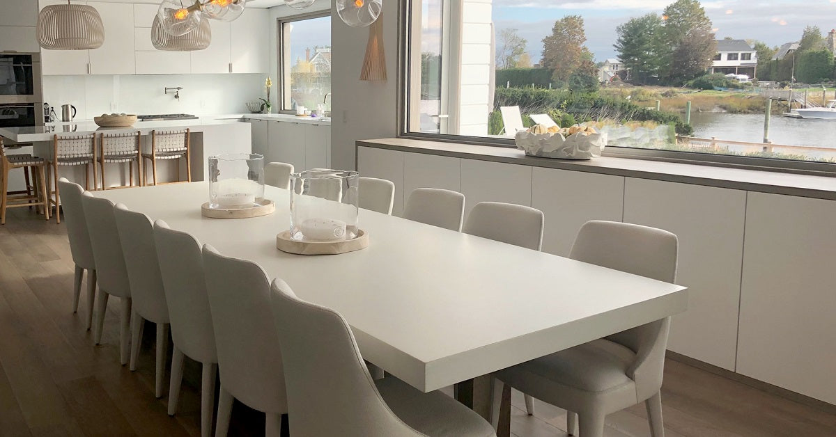 Bright kitchen with white concrete table surrounded by beige chairs.