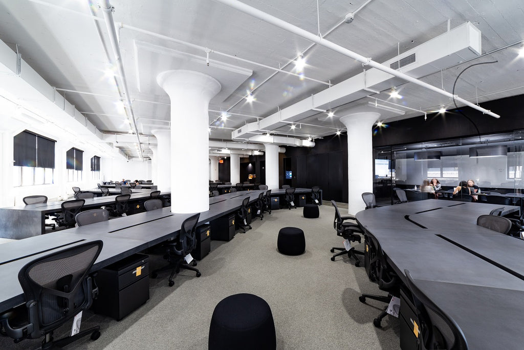 Open format office space with concrete desks in black.