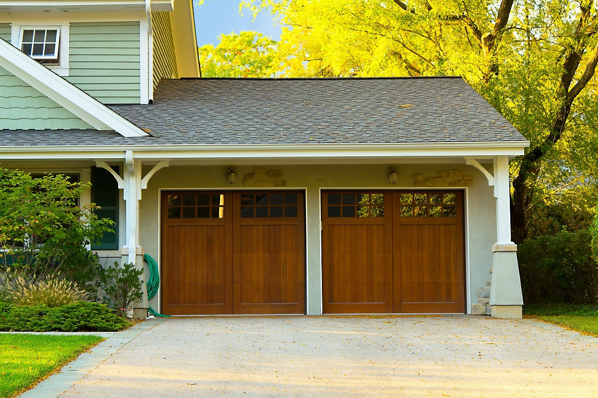 The exterior of a house with wood look garage door and green lawn.