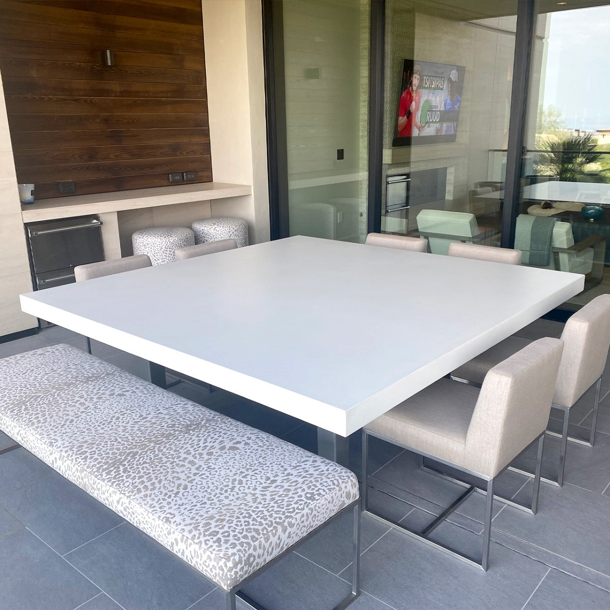 Covered patio with kitchen featuring concrete countertops and table.