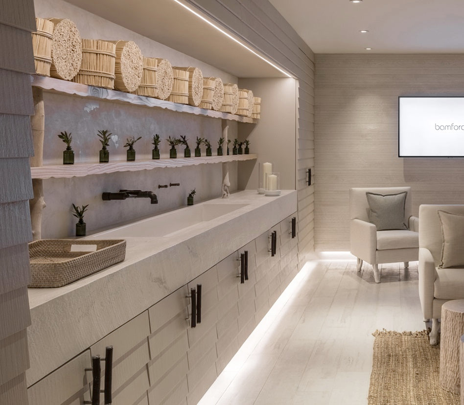 Spa with white concrete countertops and sinks with wall mounted faucets.