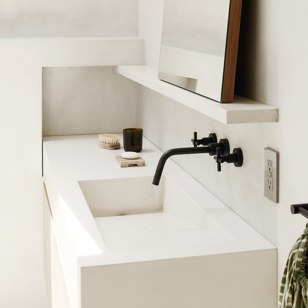 White concrete ramp sink with black wall mounted faucet.
