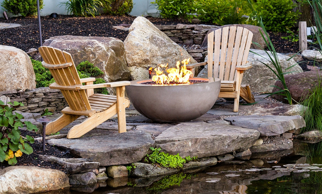 Concrete firepit on a back patio with Adirondack chairs surrounding.