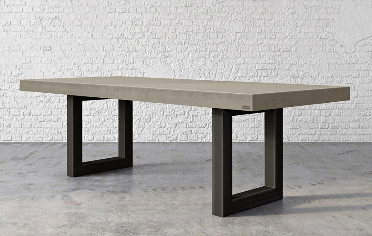 Large concrete table with metal legs in front of a white brick wall.