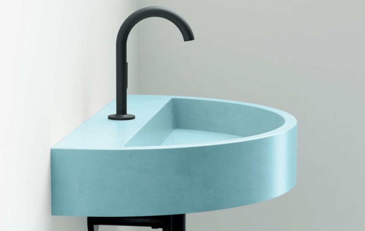 Teal wall mounted concrete sink with black fixtures.