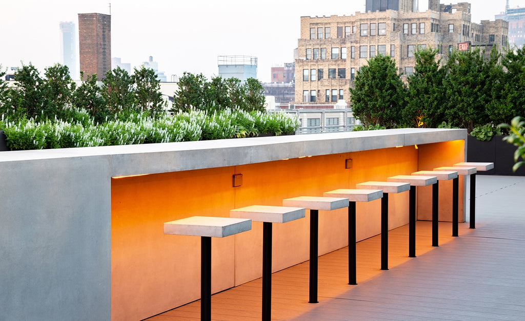 Rooftop entertaining space with concrete bar and bar stools.