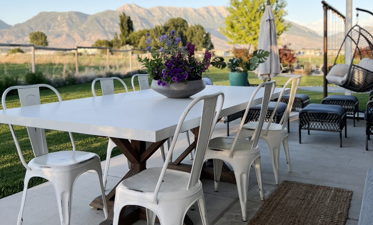 White concrete table top on a wood picnic style leg on a backyard patio with mountains in the distance.