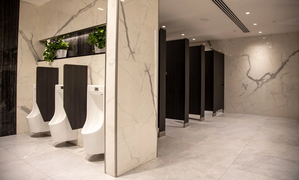 Commercial bathroom with marble floor and walls and touchless urinals.