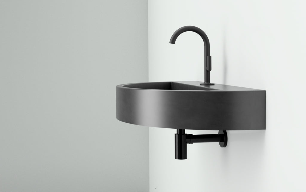 Wall mounted, curved concrete sink in black for small bathrooms.