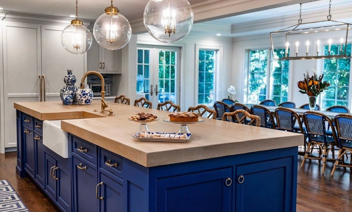 Large kitchen island with blue cabinets and wood look concrete countertop.