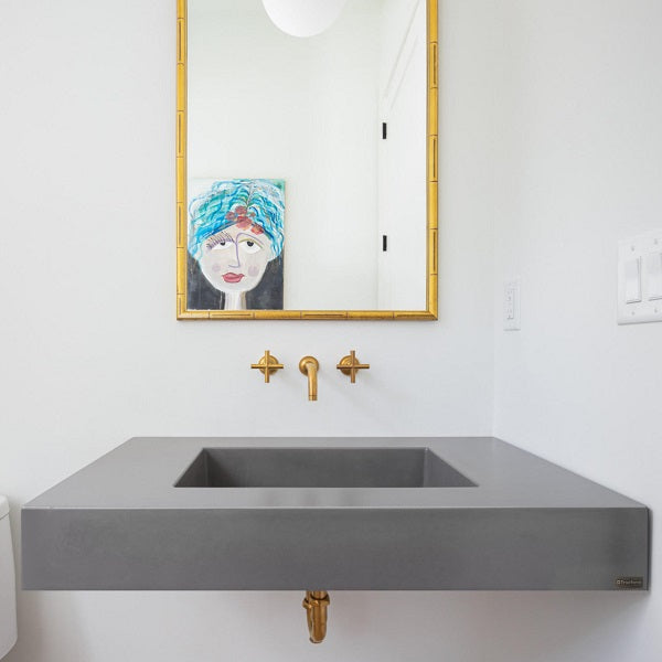 Wall mounted gray concrete bathroom sink with mirror above.