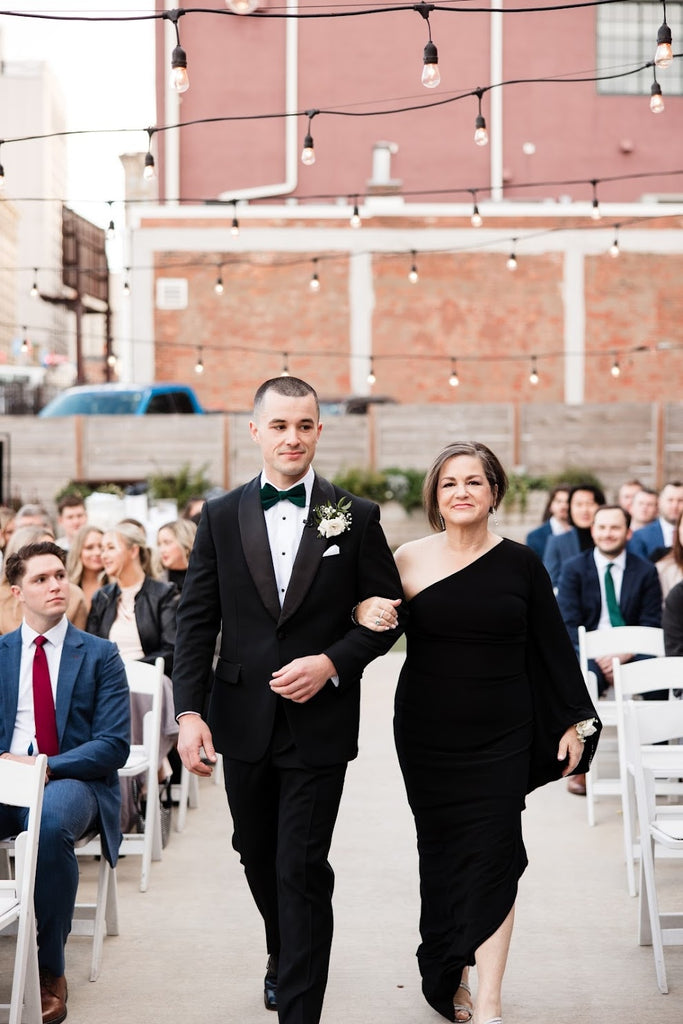 Groom and mom walk wedding aisle