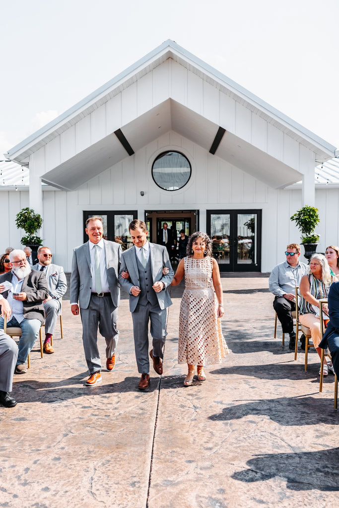 mother and father walk groom down aisle