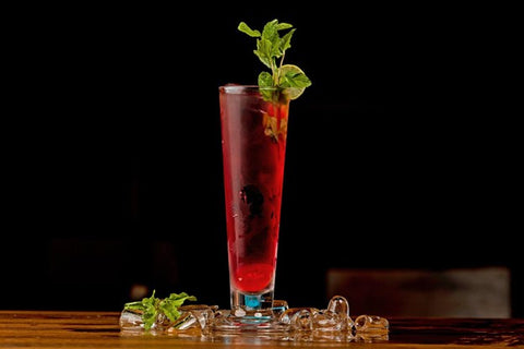 A non-alcoholic cocktail in a tall glass against a dark background