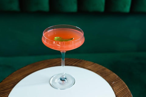 Non-alcoholic rhubarb gimlet in a wine glass on a table