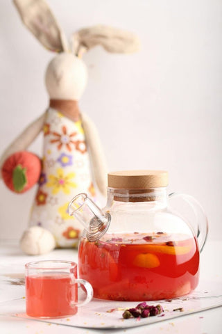 a kettle and cup of strawberry tea refresher on a white table