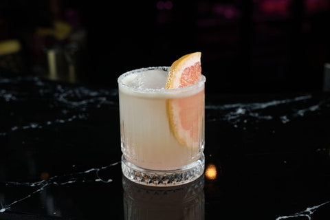 non-alcoholic Paloma with a grapefruit wedge on a marble counter