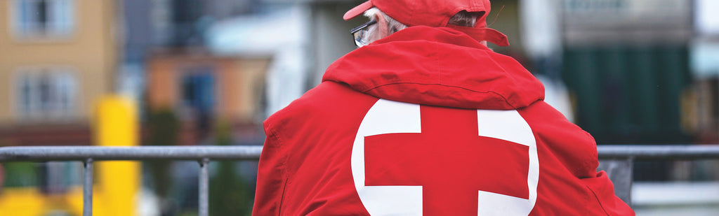 Image of a man wearing a red jacket with red cross at the back