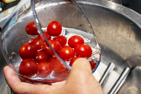 Washing cherry tomatoes in glass bowl